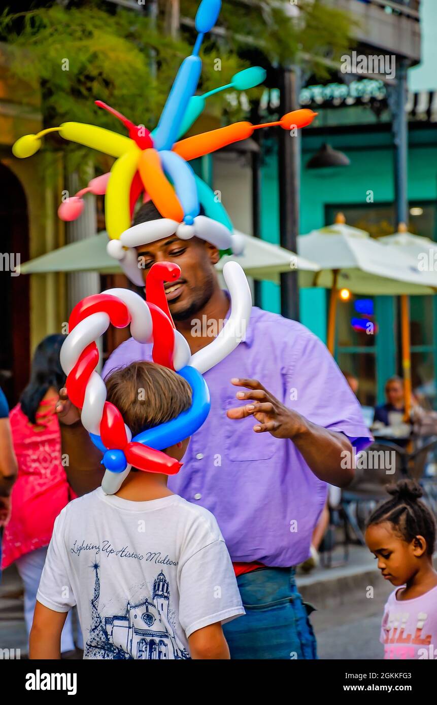 Un uomo fa gli animali della mongolfiera per i bambini su Dauphin Street durante la seconda passeggiata dell'arte del venerdì, 10 settembre 2021, in Mobile, Alabama. Foto Stock