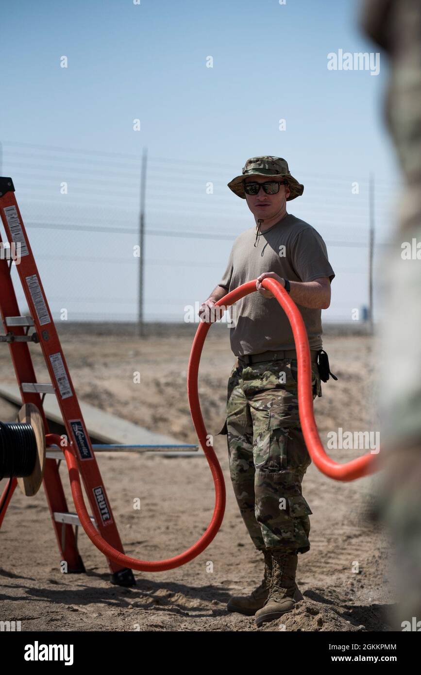 U.S. Air Force staff Sgt. Kelby Ramsey, 380esimo tecnico di trasmissione in radiofrequenza della Squadron Expeditionary Communications, stende il condotto interno durante l'installazione di stazioni base e antenne alla base aerea al Dhafra, Emirati Arabi Uniti, 20 maggio 2021. L'installazione migliorerà la capacità dei manutentori di comunicare lungo la linea di volo. Foto Stock