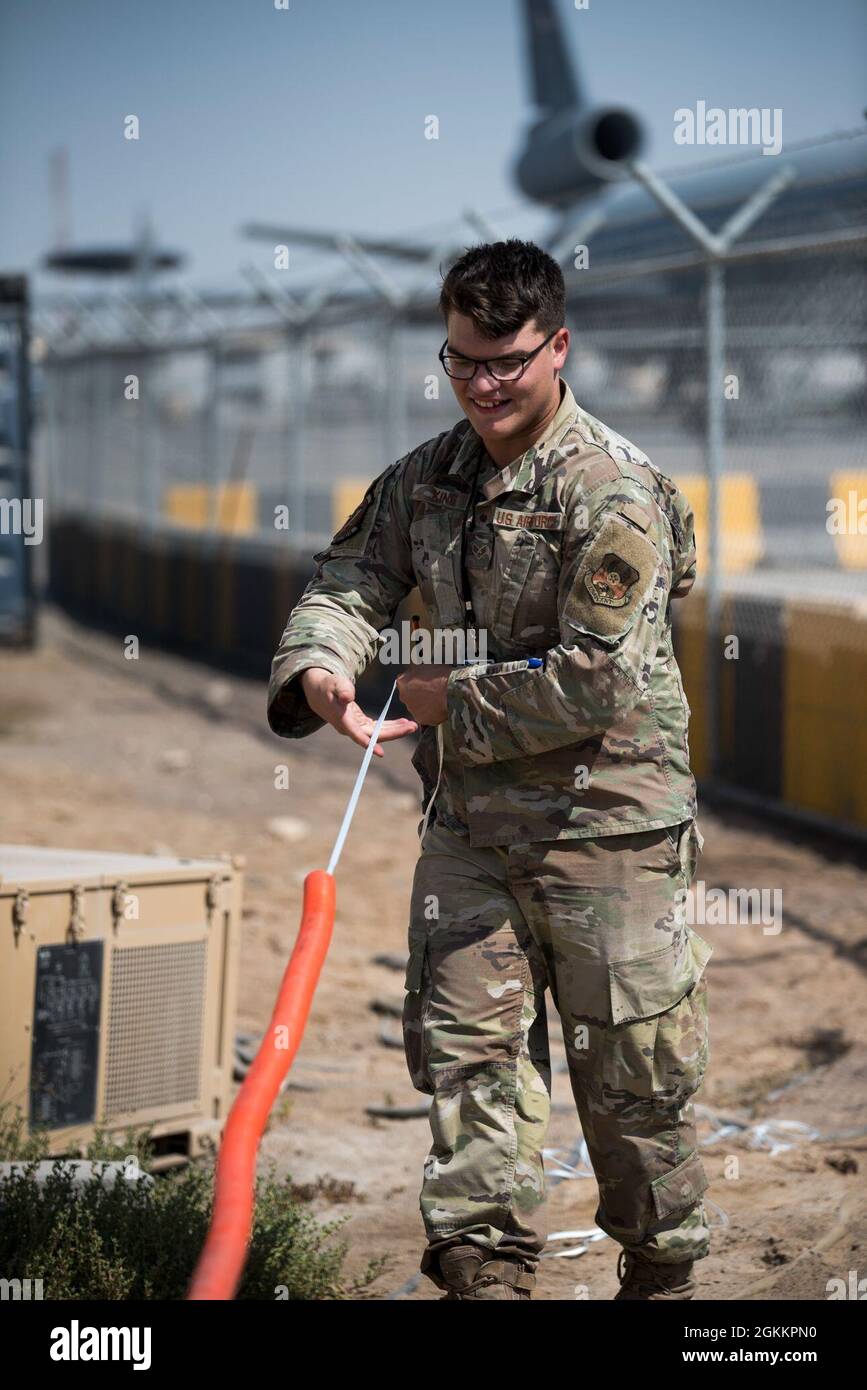 U.S. Air Force Senior Airman Dakota King, 380th Expeditionary Communications Squadron radio frequency transmission Technician, stende internal-dotto durante l'installazione di stazioni base e antenne presso la base aerea al Dhafra, Emirati Arabi Uniti, 20 maggio 2021. L'installazione migliorerà la capacità dei manutentori di comunicare lungo la linea di volo. Foto Stock
