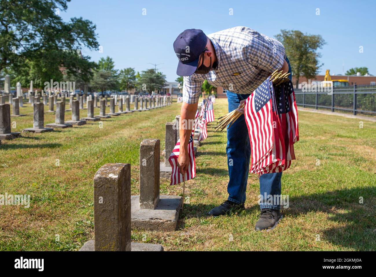 Jonathan Echols, membro fondatore del Norfolk Naval Shipyard Veteran Employee Readiness Group, stese bandiere sulle tombe dei membri caduti durante la cerimonia annuale di stallonamento della bandiera presso il cimitero navale Captain Ted Conaway Memorial nel Naval Medical Center di Portsmouth (NMCP), maggio 27. Foto Stock