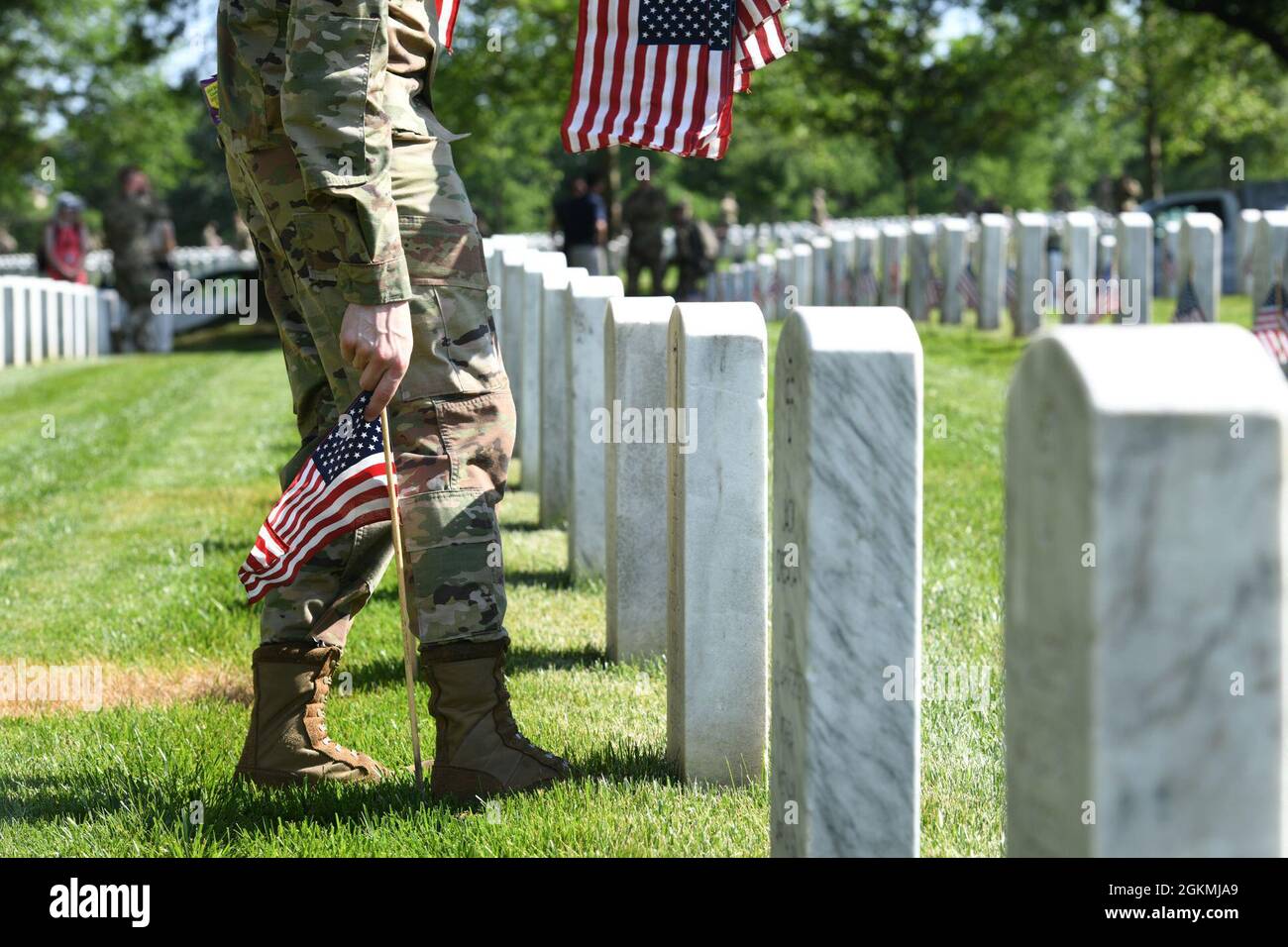 U.S. Air Force Airman 1st Class Michael Hester, guardiana cerimoniale della Guardia d'onore dell'Aeronautica militare statunitense, posiziona una bandiera americana nel cimitero nazionale di Arlington, Arlington, Va., durante "Flags-in", maggio 27, 2021. Ogni anno prima del Memorial Day, più di 280,000 bandiere sono collocate ad ogni testa del cimitero in onore degli eroi caduti delle nazioni. Foto Stock