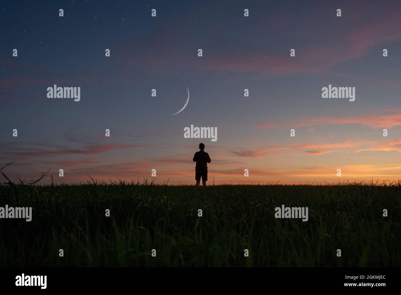 Grandangolo di persona da dietro con la luna e le stelle durante il tramonto Foto Stock