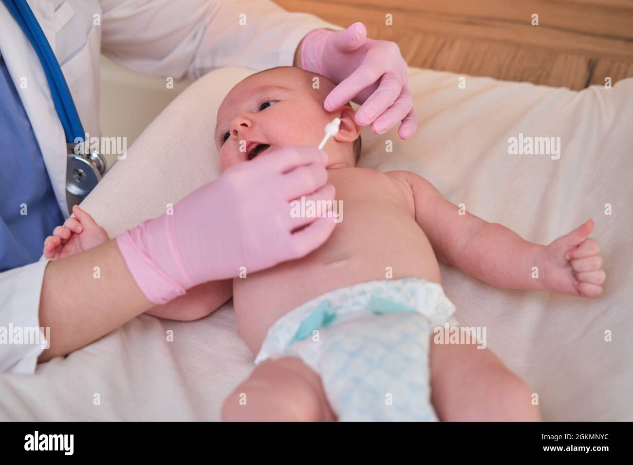Il medico effettua l'igiene del naso e delle orecchie del neonato con un  bastoncino di cotone. L'infermiera in uniforme sfrega la pelle di un bambino  Foto stock - Alamy