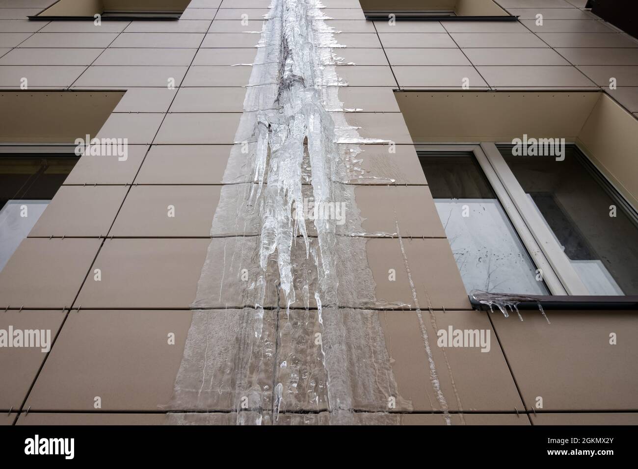 Pipa di pioggia congelata su un edificio di appartamenti. Ghiaccio sulla parete dell'edificio. Foto Stock