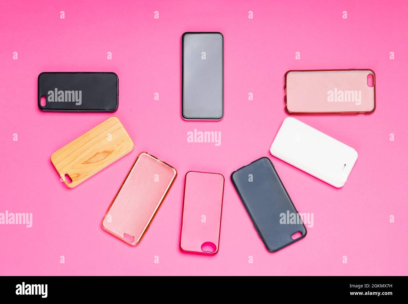 Possibilità di scelta tra cover posteriori in plastica multicolore per telefoni cellulari sfondo rosa con uno smartphone sul lato Foto Stock