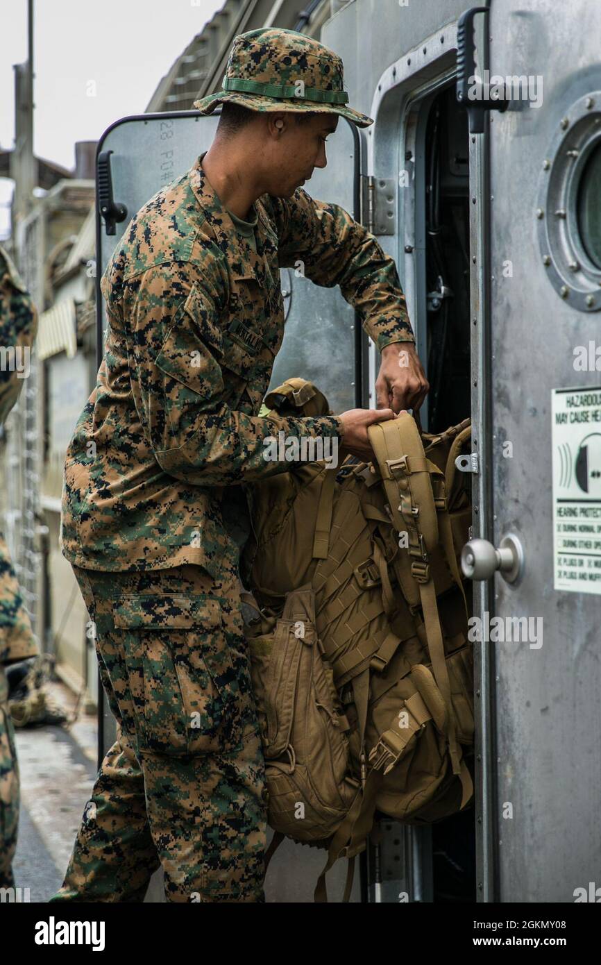 CPL del corpo marino degli Stati Uniti. Jason Montalvo, ingegnere di combattimento con Alpha Company, 9° Battaglione di supporto tecnico, 3d Marine Logistics Group (MLG), carica il suo equipaggiamento in un cuscino d'aria dell'imbarcazione di atterraggio (LCAC) sulla base navale di White Beach, Okinawa, Giappone, 1 giugno 2021. Marines di 3d MLG e marinai di Naval Beach Unit 7 integrati per il carico e il trasporto di personale e attrezzature a supporto della torre di osservazione Poseidon esercizio. NBU-7 è un'unità operativa, schierata in avanti che contribuisce direttamente alle capacità fondamentali del potere marittimo degli Stati Uniti facilitando il movimento delle truppe, delle attrezzature, dei veicoli e. Foto Stock