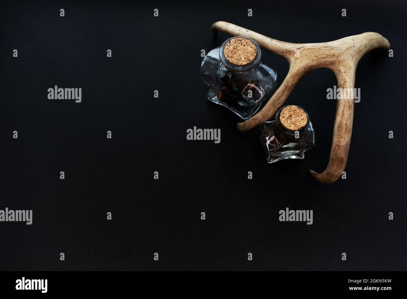 Due bottiglie magiche di pozione di alchimia su sfondo di carta nero. Mockup, spazio di copia. Foto Stock