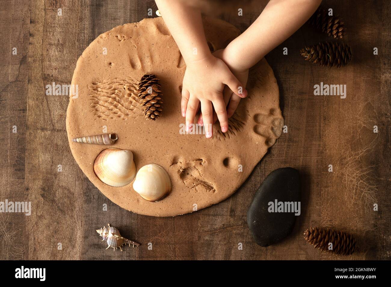 I bambini giocano con l'impasto di sale sul tavolo da cucina. Le mani modellano l'argilla con le proprie mani per creare giocattoli caserecci a vita zero. Lezione creativa con te Foto Stock