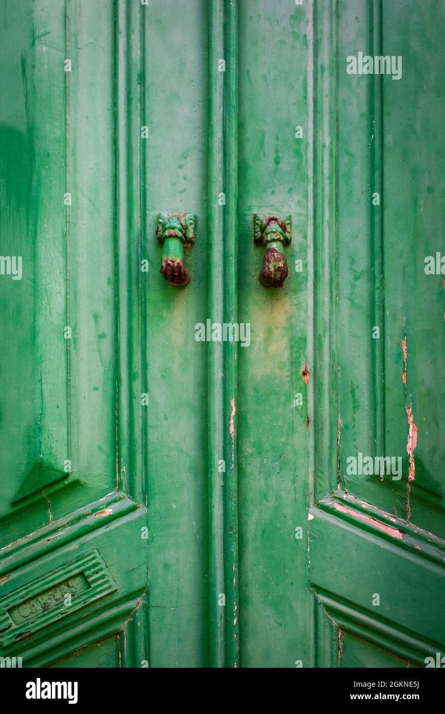 Dettaglio della porta in legno verde d'epoca con due bussole a forma di mano di donna. Immagine verticale Foto Stock