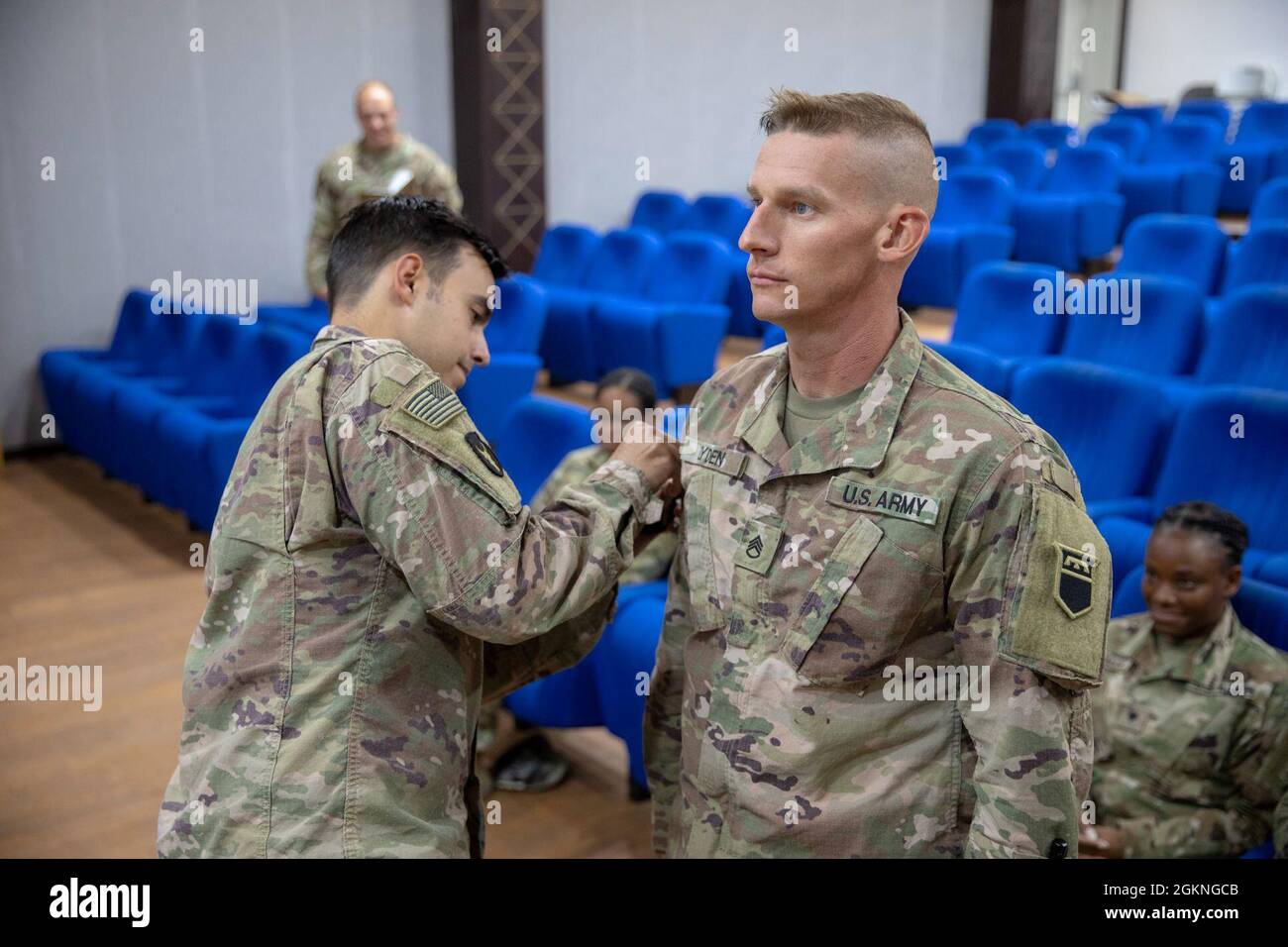 Lance Breon, un leader di Hazard Assessment Platoon con il 318th Chemical Biological Radiological and Nuclear Defense Company, Task Force Spartan, pone un'insegna a manica destra sul leader di squadra Recon 2, staff Sgt. Trenton Lyden, presso il Joint Training Centre, Giordania, 05 giugno 2021. Un'insegna a manica destra è un'indicazione del servizio di un soldato in o a sostegno di operazioni di combattimento a terra. Foto Stock