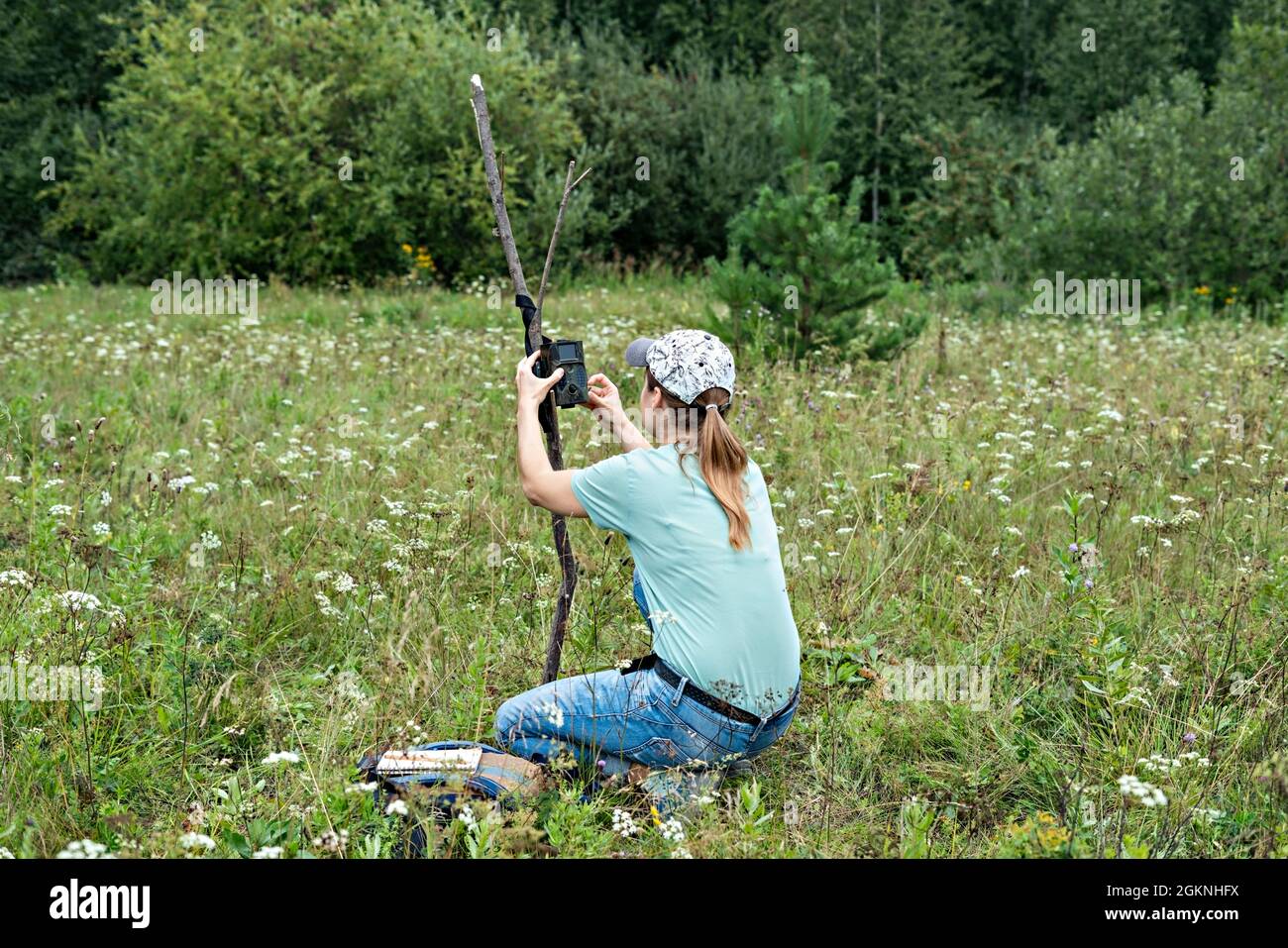 Giovane donna scienziata biologa zoologo imposta trappola fotocamera per osservare animali selvatici in estate foresta taiga per raccogliere dati scientifici ambientale Foto Stock
