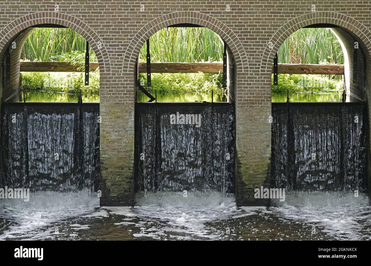 Dettaglio di uno stramazzo storico che alimenta un canale con acqua da un fiume Foto Stock