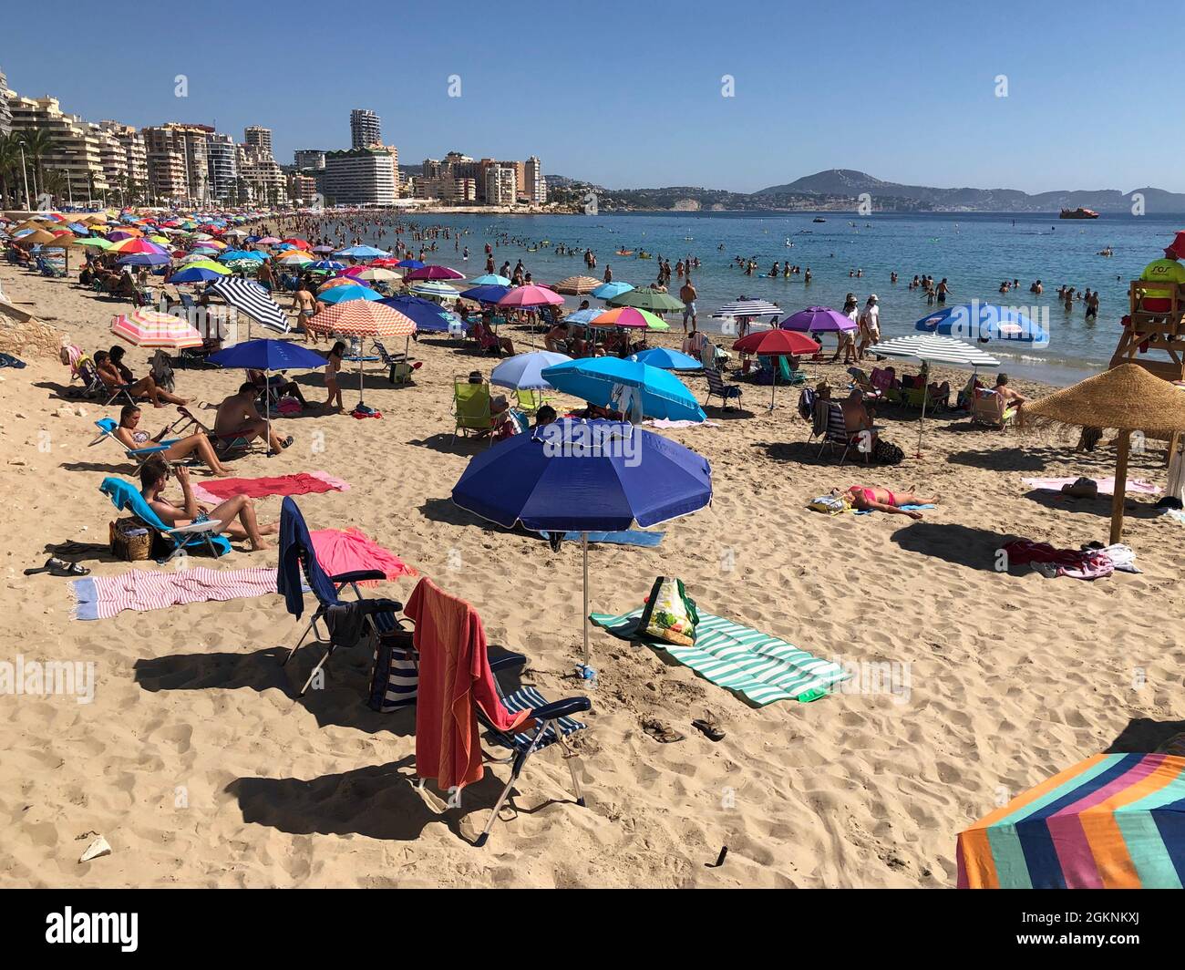 Vista della spiaggia affollata a mezzogiorno nella località mediterranea estiva Calpe, Spagna. Questa città fa parte della famosa località turistica Costa Blanca. Foto Stock