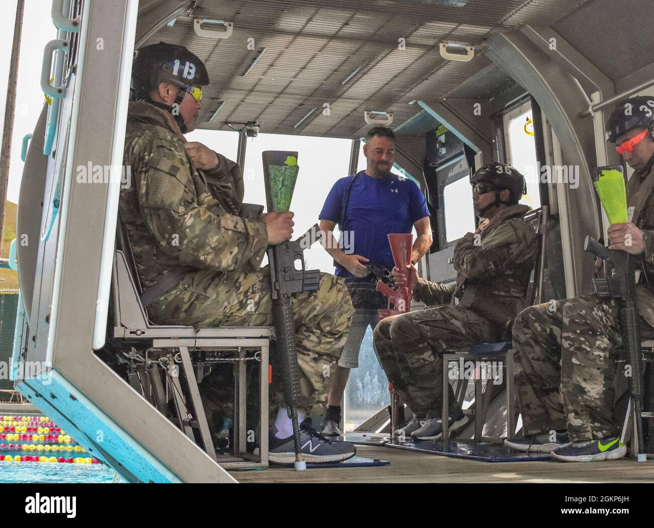 I soldati della Guardia Nazionale dell'Esercito delle Hawaii con il terzo Battaglione, il 126esimo Regiment dell'Aviazione e il 1st Battaglione, il 189esimo Regiment dell'Aviazione afferrano sopra il loro gilet di sicurezza e l'arma prima di condurre l'addestramento di sopravvivenza dell'acqua dell'elicottero sopra (OSPITE), Kaneohe, Hawaii, 10 giugno 2021. L'addestramento consiste nell'imparare come respirare sott'acqua con un sistema di respirazione di emergenza (EBS), simulando un rollover sott'acqua con il addestratore di discesa dell'acqua bassa (SWET) seguito da un addestratore simulato dell'uscita dell'aereo. Foto Stock