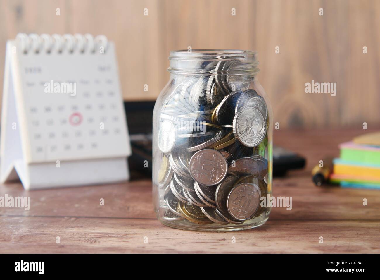 monete in un vaso e calendario sul tavolo Foto Stock