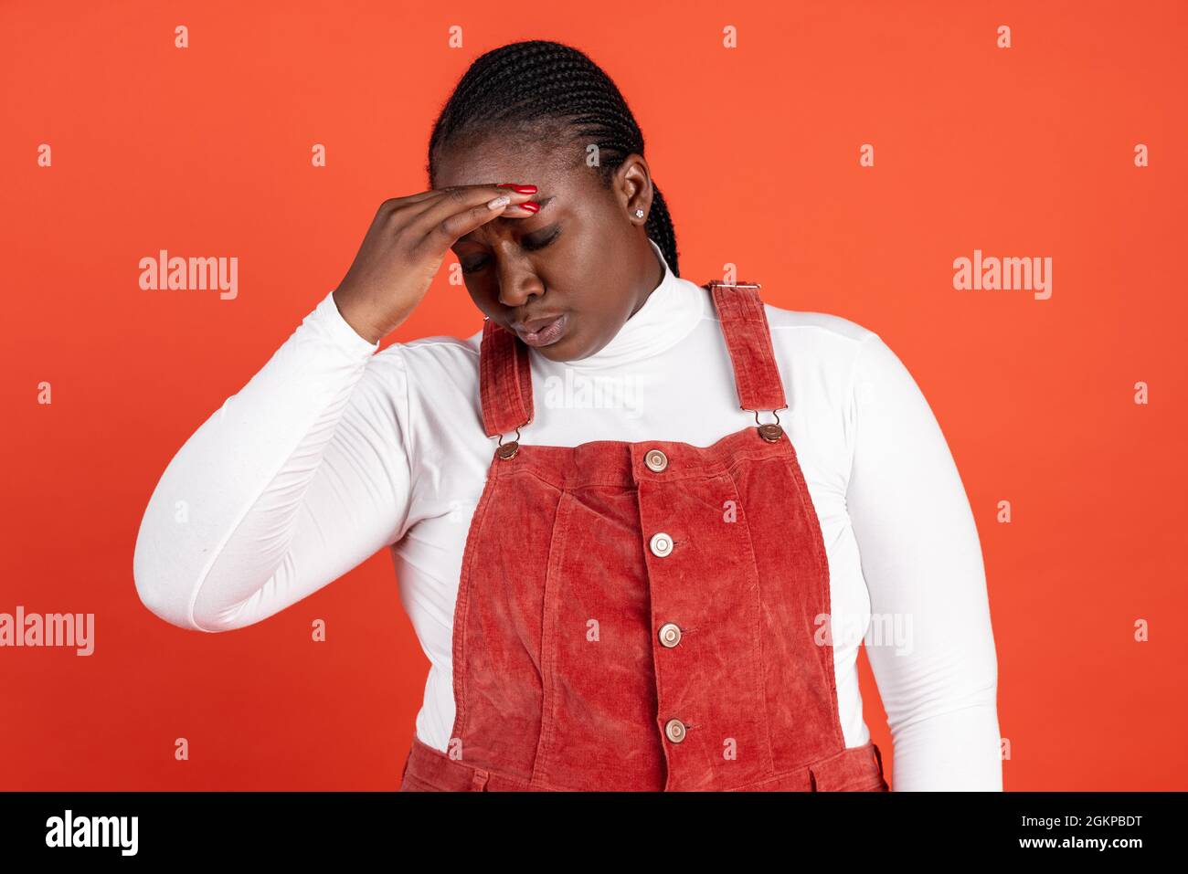 Ritratto luminoso di donna triste africana isolato su sfondo rosso studio. Concetto di emozioni umane, espressione facciale, bellezza naturale, bodypositive Foto Stock