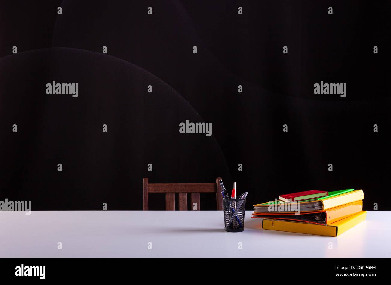 Pentola matite accanto ai libri impilati, forniture scolastiche su scrivania bianca con struttura lavagna in background. Vista laterale, spazio di copia. Apprendimento, istruzione Foto Stock