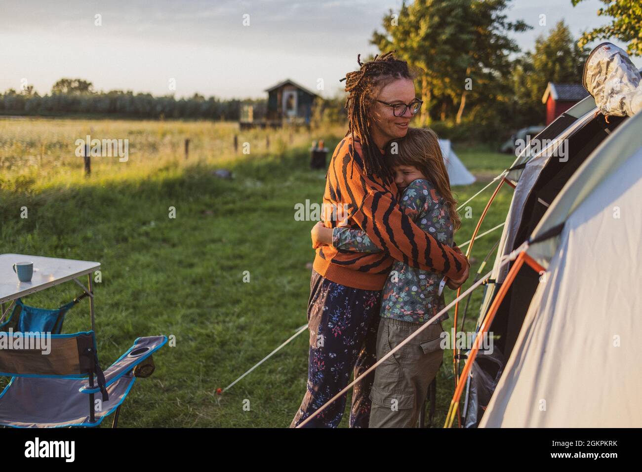 Madre e figlia si abbraccia di fronte alla tenda del campeggio Foto Stock