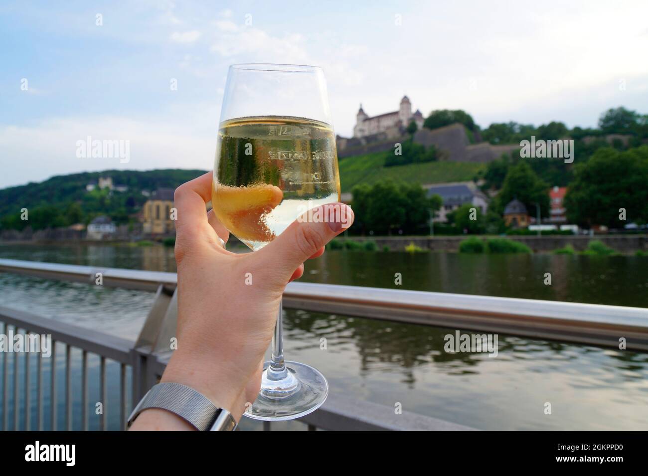 Un bicchiere di vino bianco semi-secco croccante con la Fortezza Marienberg e i vigneti sullo sfondo in una bella giornata di primavera a Wuerzburg (Germania) Foto Stock