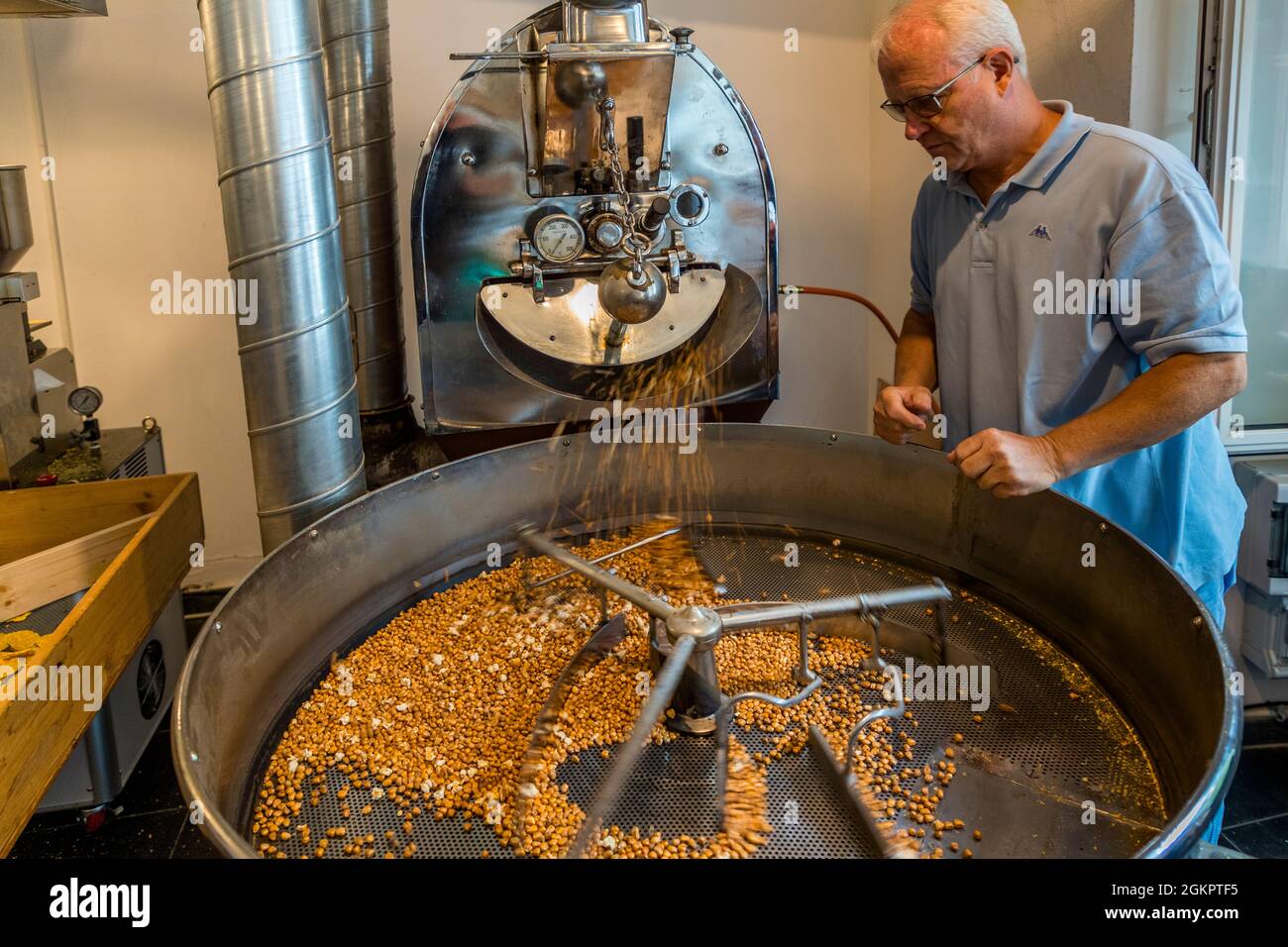 Ilario Garbani controlla il processo di tostatura dei chicchi di mais che sono la materia prima della farina Bona. Circolo d'Onsernone, Svizzera Foto Stock