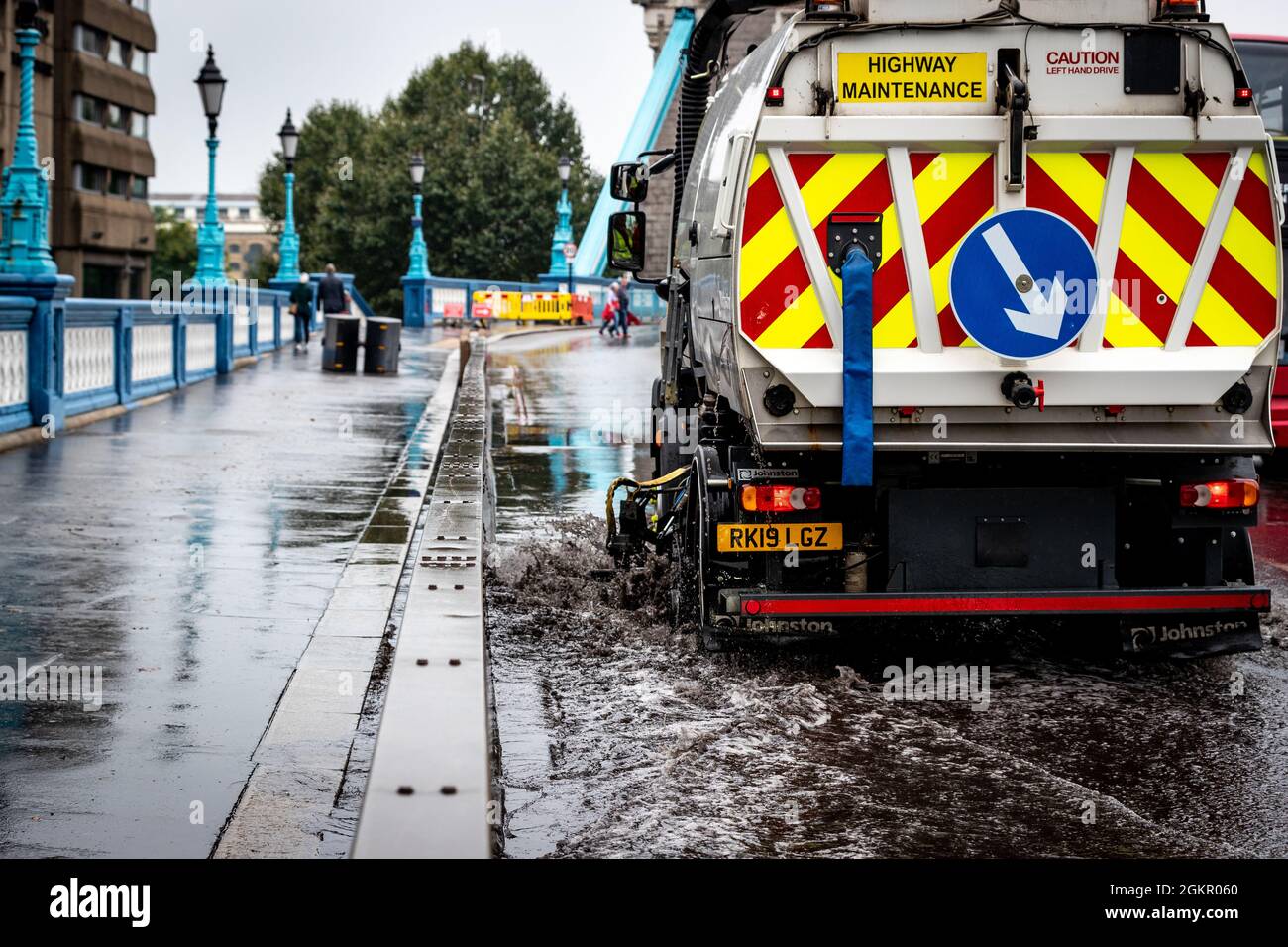 Un veicolo di manutenzione utilizza una pompa a vuoto per aspirare l'acqua di alluvione sul Tower Bridge. Foto Stock