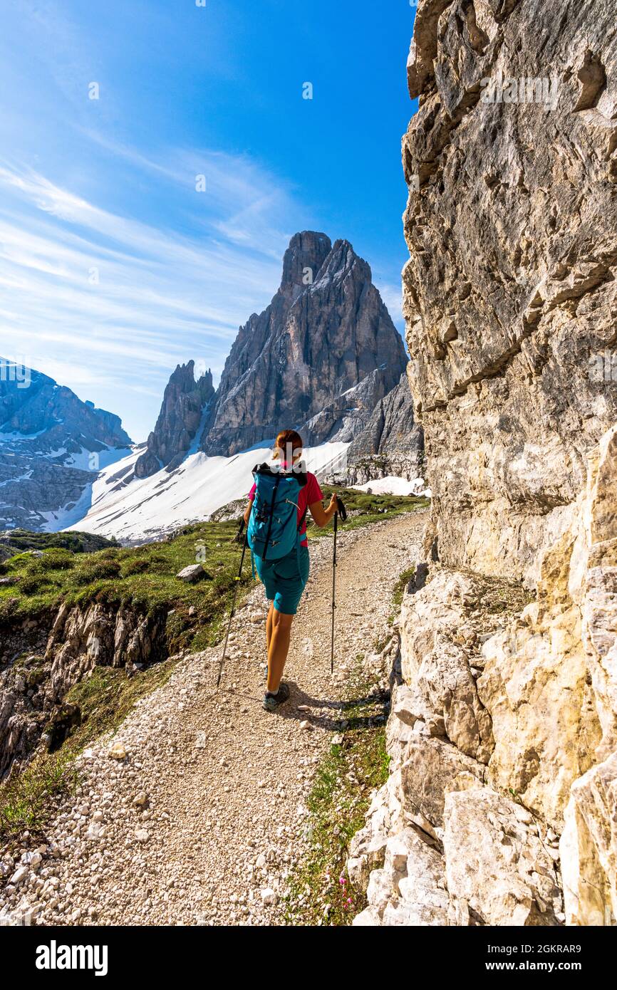 Donna zaino in spalla con racchette da trekking che si gode la vista della Croda dei toni dal sentiero, Dolomiti di Sesto, Alto Adige, Italia, Europa Foto Stock
