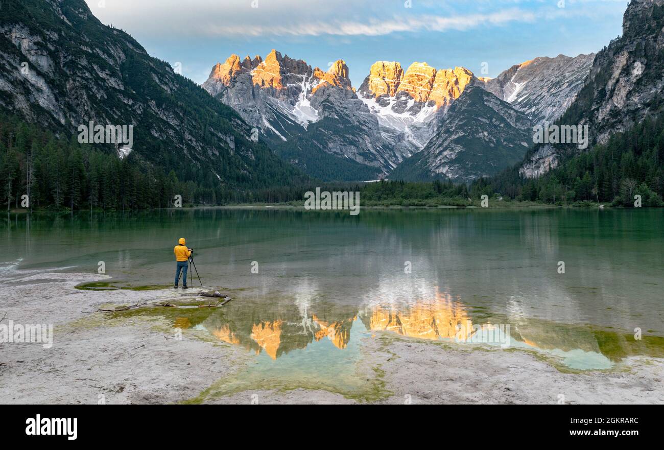 Fotografa con treppiede ammirando le Dolomiti all'alba dal lago di Landro, Dolomiti, provincia di Bolzano, Alto Adige, Italia, Europa Foto Stock