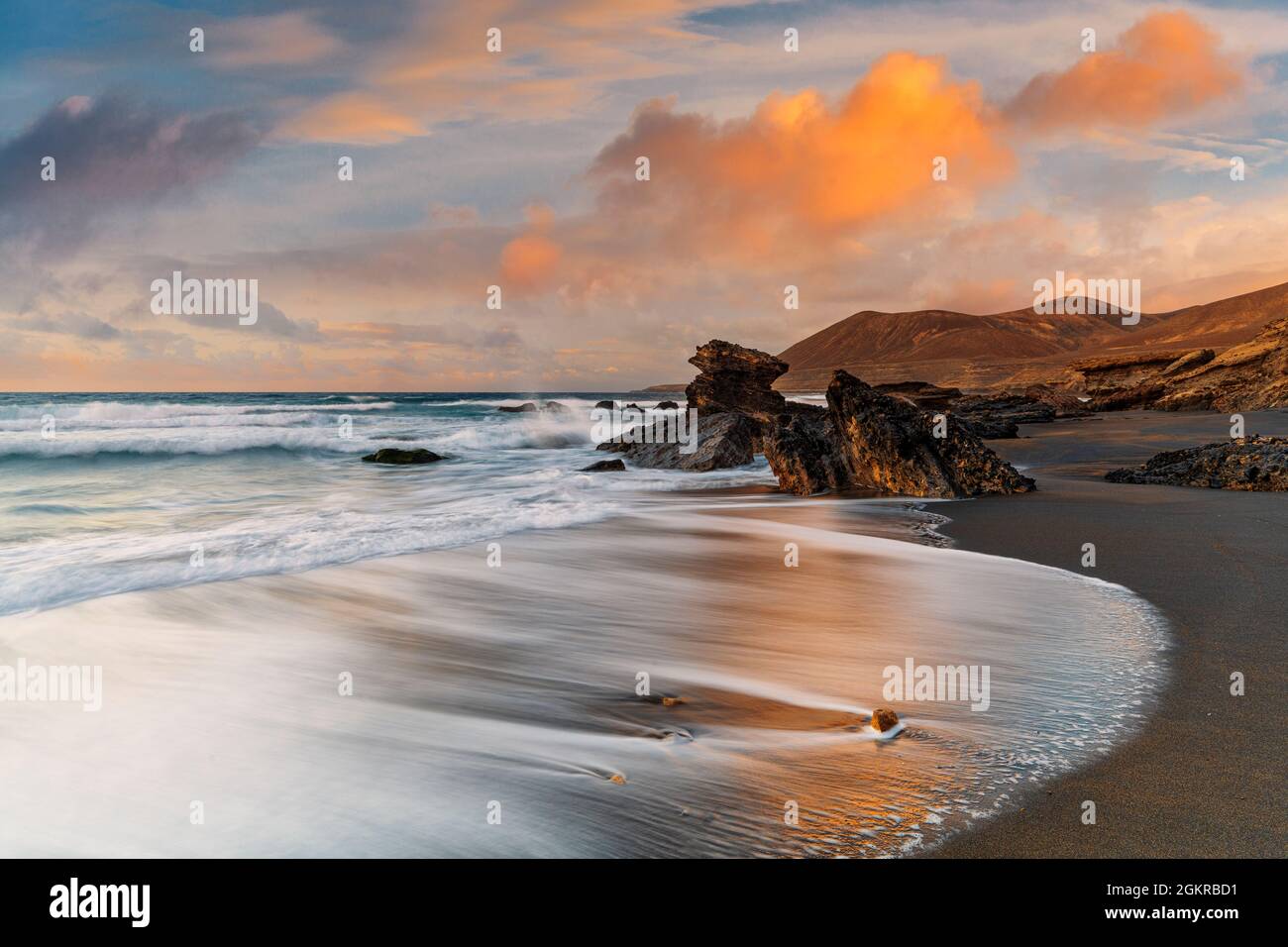 Onde che si infrangono sulla spiaggia sabbiosa Playa de la Solapa al tramonto, Fuerteventura, Isole Canarie, Spagna, Atlantico, Europa Foto Stock