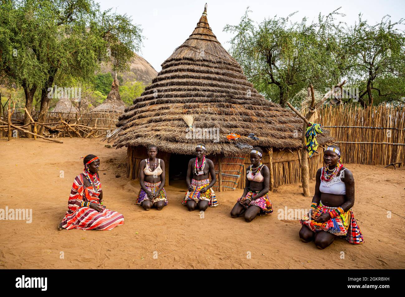 Giovani donne di fronte ad una capanna di villaggio tradizionale della tribù laarim, colline di Boya, Equatoria orientale, Sudan del Sud, Africa Foto Stock