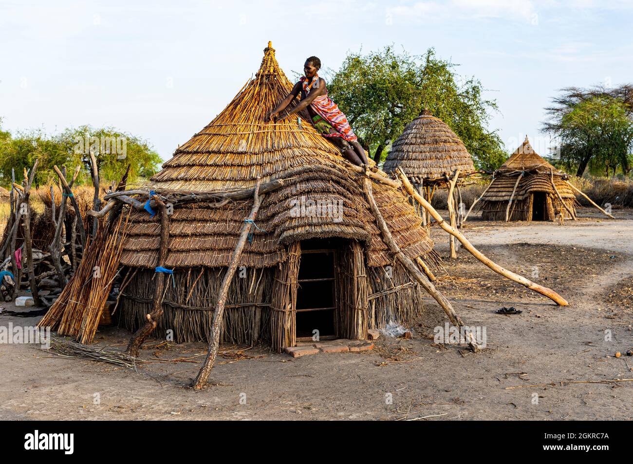Donna che ripara un tetto di una capanna tradizionale della tribù Toposa, Equatoria Orientale, Sudan del Sud, Africa Foto Stock