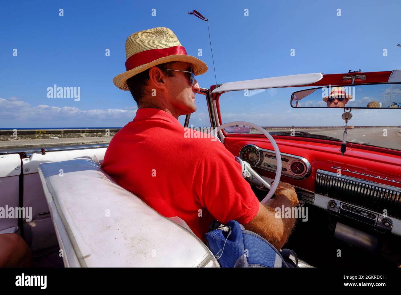 L'uomo in paglia guida l'auto d'epoca lungo Malecon, l'Avana, Cuba, le Indie Occidentali, l'America Centrale Foto Stock