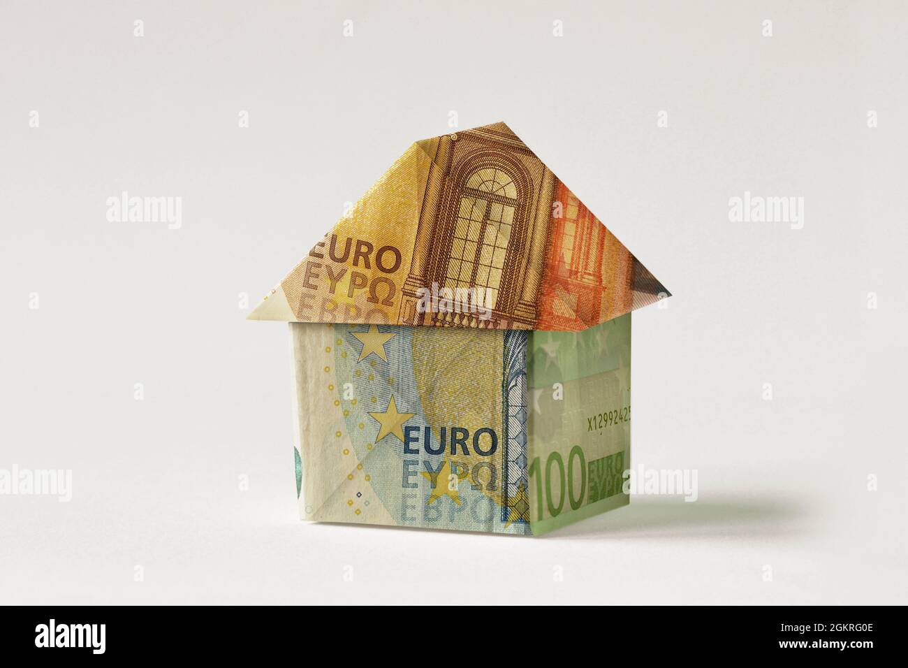 Casa Origami fatta di banconote in euro su sfondo bianco - concetto di investimento immobiliare, ipoteca, assicurazione casa e prestito Foto Stock