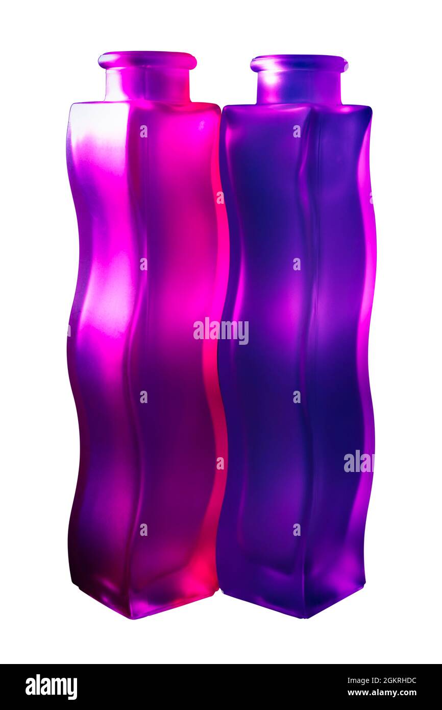 Un paio di vasi di vetro ondulati che riflettono la luce rosa e viola, isolati su sfondo bianco, con percorso di taglio Foto Stock