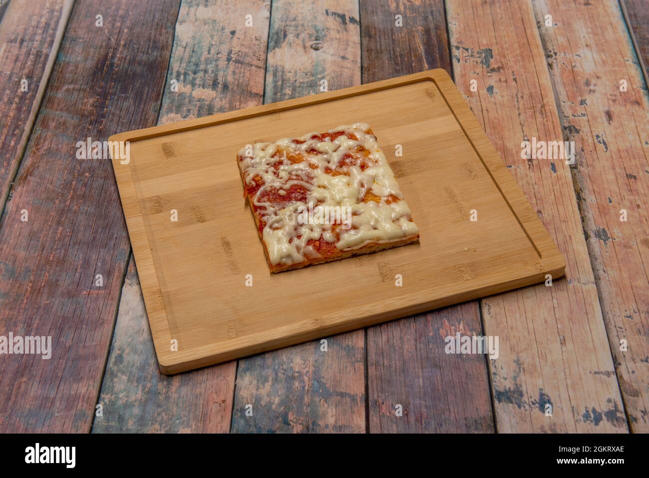 Pezzo quadrato di pizza margherita su piatto di bambù su tavola di legno  Foto stock - Alamy