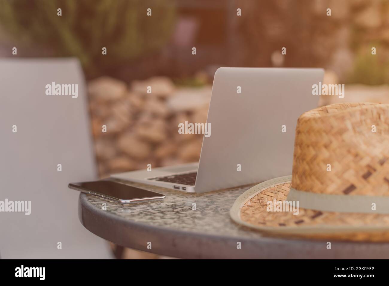 Lavoro sul retro vacanza spazio di lavoro terrazza con computer portatile, smartphone e spiaggia paglia cappello Foto Stock