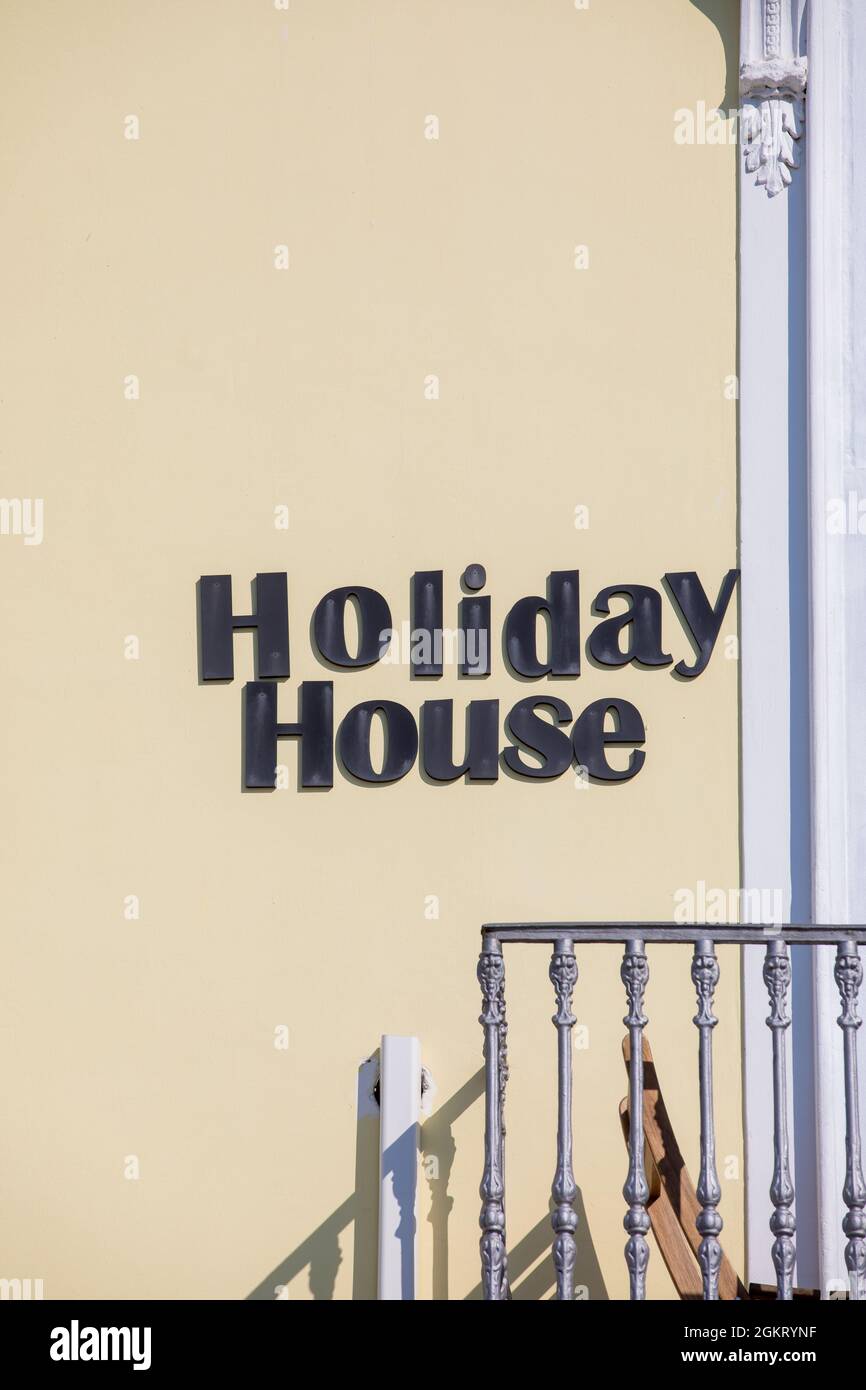 Casa per le vacanze. Testo delle parole dell'hotel apparsi sulla parete esterna. Vicino alla ringhiera di un balcone. Parete gialla. Foto Stock