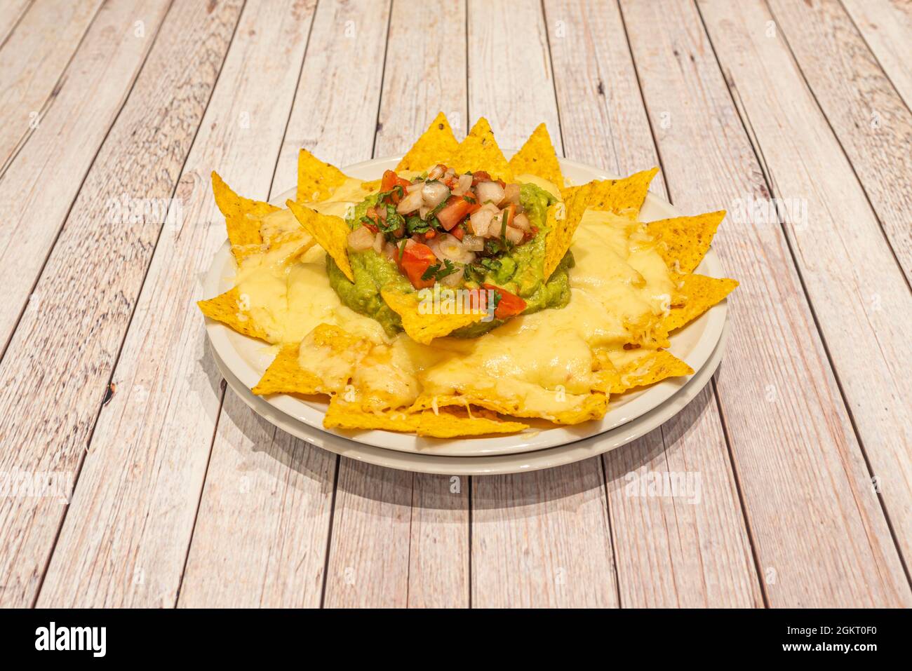 Ricetta per nachos con guacamole e formaggio fuso presentato come un fiore di mais commestibile Foto Stock