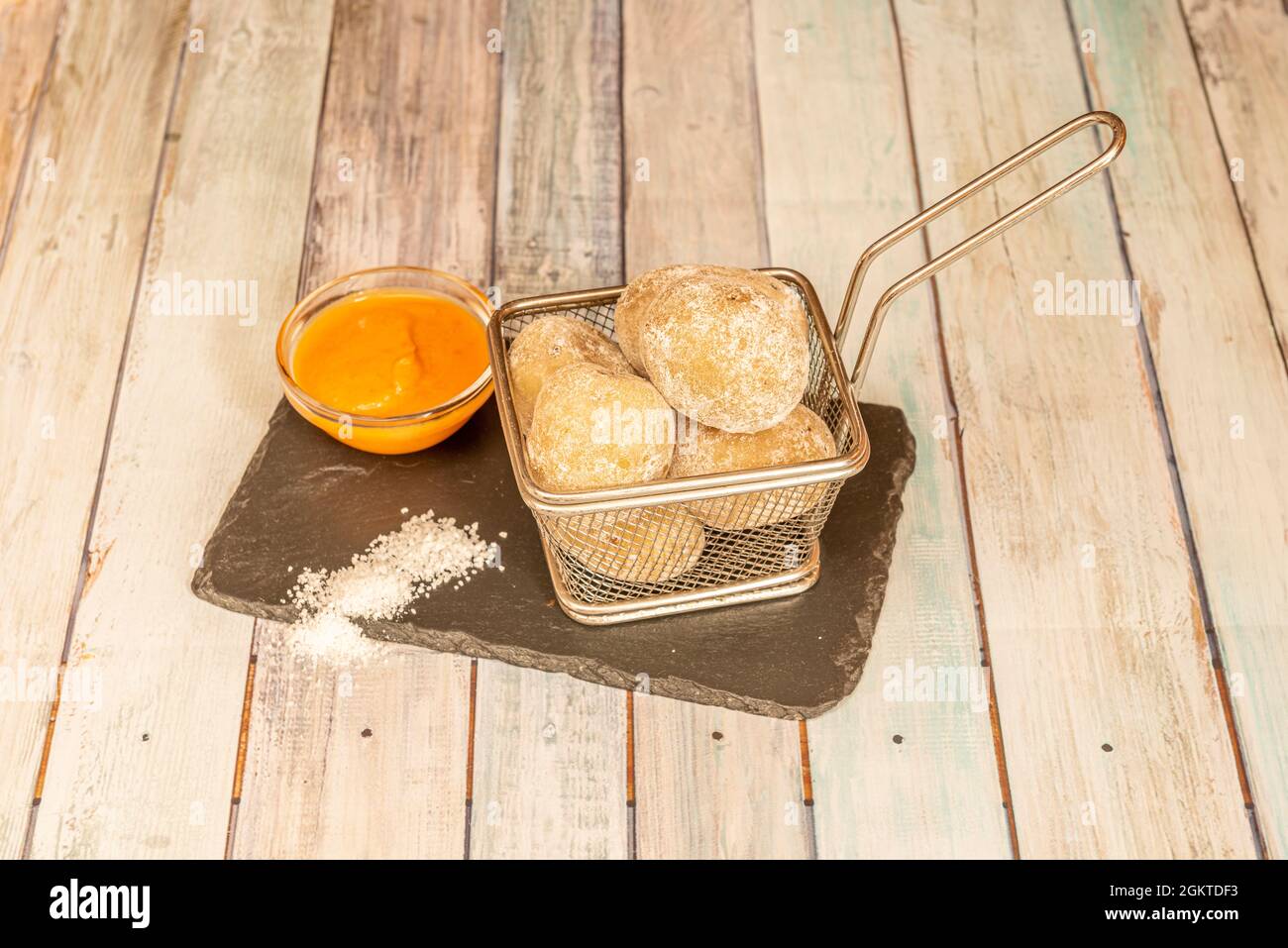 Porzione di patate grinzite in un cestino di metallo per friggere con salsa mojo rosso per immergerla Foto Stock