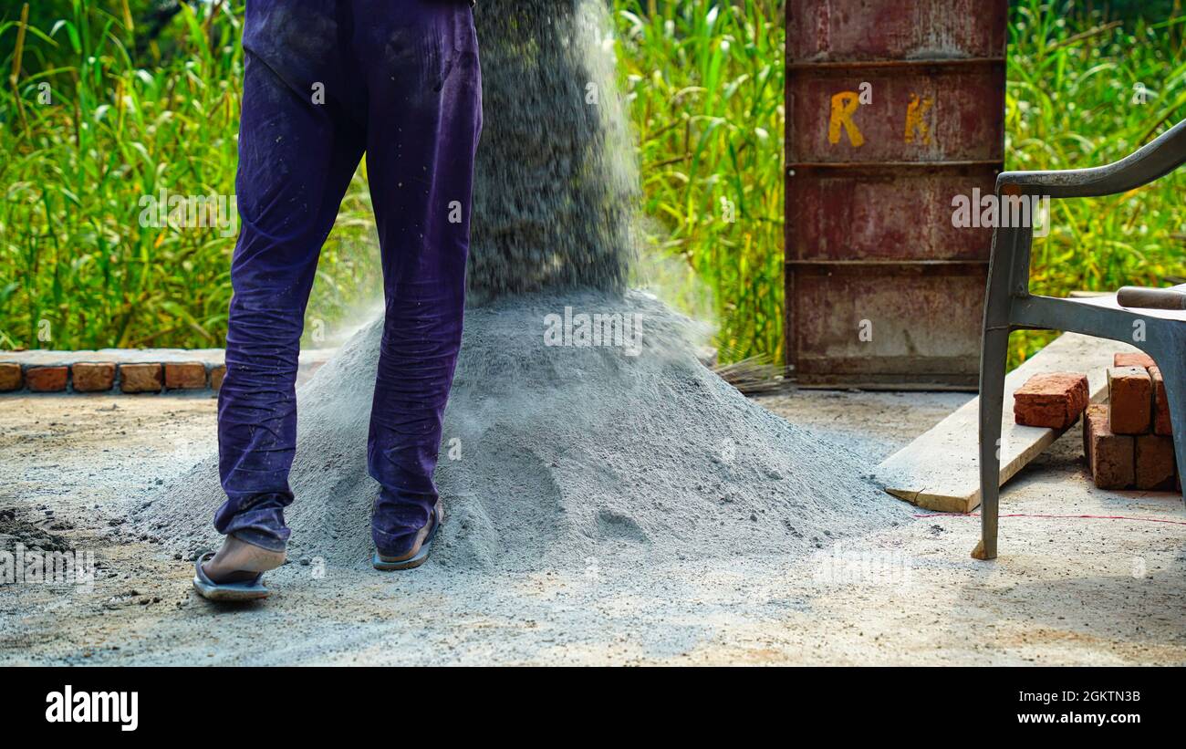 Il lavoro indiano ha messo giù cemento su terra per fare la pasta concreta. Scatto del cantiere Foto Stock