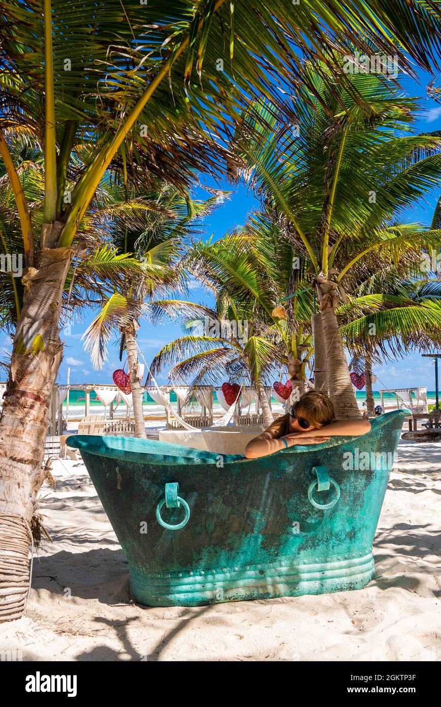 Donna che si rilassa in stile retrò vasca da bagno in metallo presso il resort sulla spiaggia Foto Stock