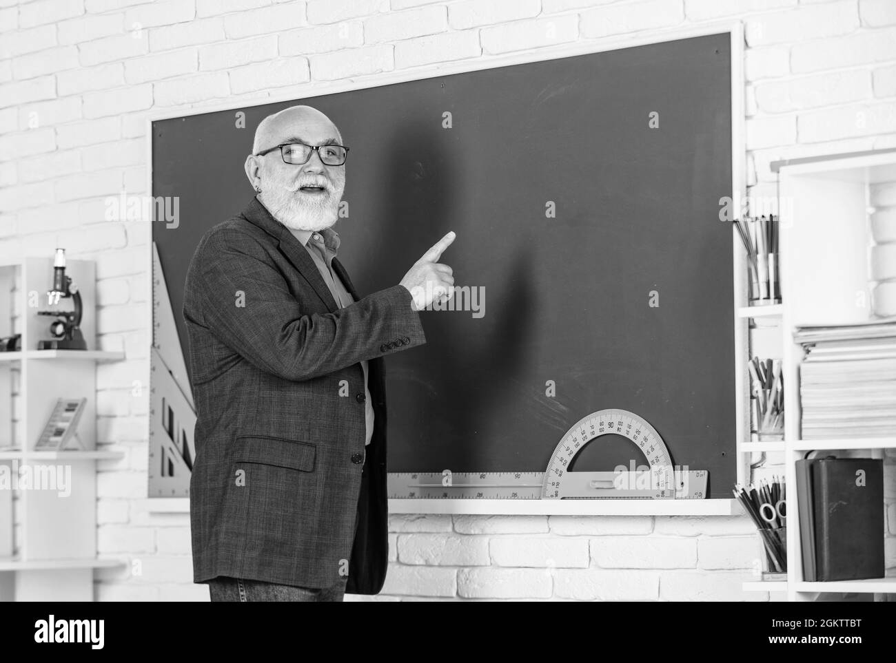 corsi universitari. stem in classe. insegnante di anziano uso strumento in lavagna. tutor con bearded in occhiali. torna a scuola. dominatore di protactor. imparare Foto Stock