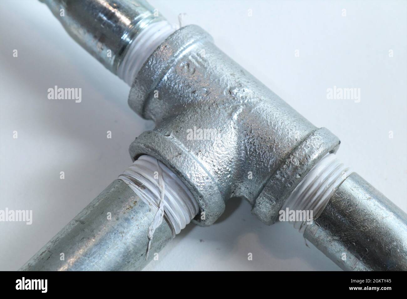 Tubo di raccordo a T galvanizzato. La zincatura è il processo di applicazione di un rivestimento protettivo di zinco su acciaio o ferro, per prevenire la ruggine Foto Stock