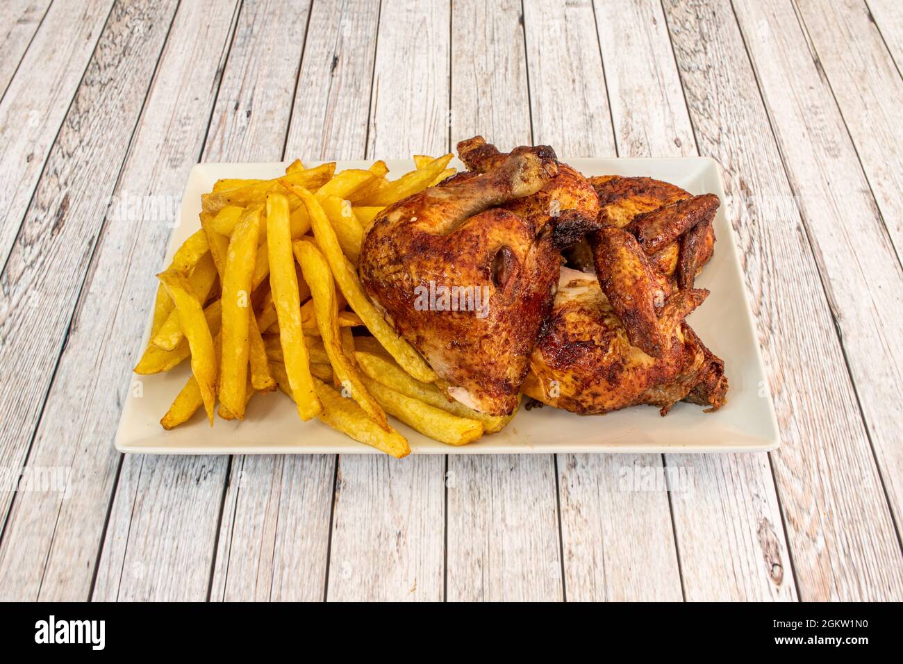 Vassoio di pollo arrosto tritato e un lato di patatine fatte in casa su un tavolo leggero Foto Stock