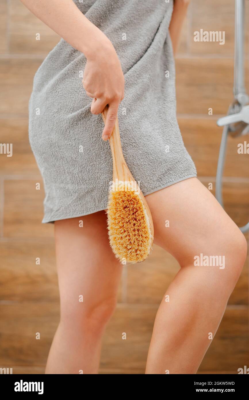 Donna in asciugamano grigio nella doccia con una spazzola per massaggio in  legno per pulire la pelle Foto stock - Alamy