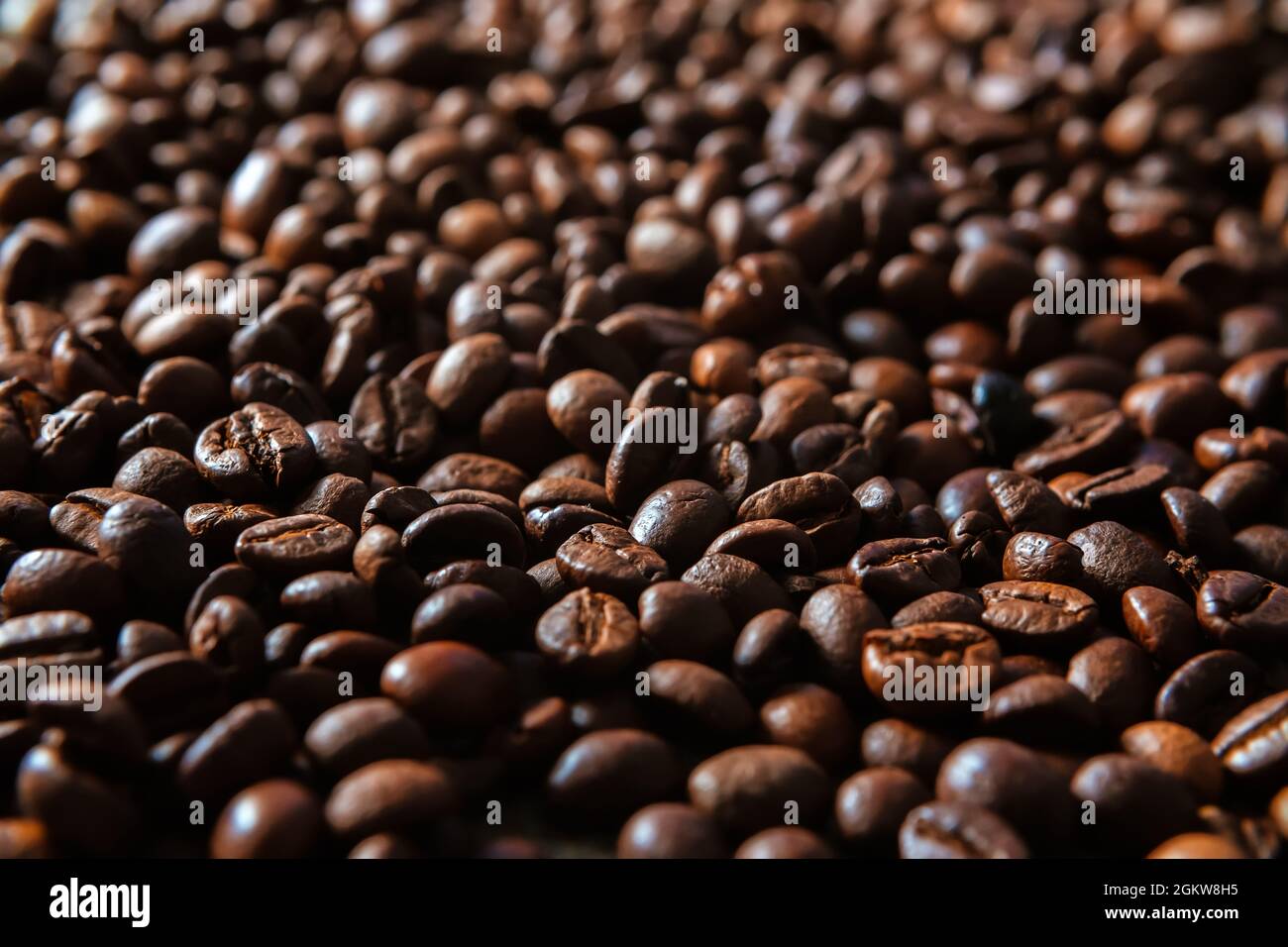 Sfondo di chicchi di caffè tostati scuri. Un mucchio grande di semi di espresso tostati in primo piano Foto Stock