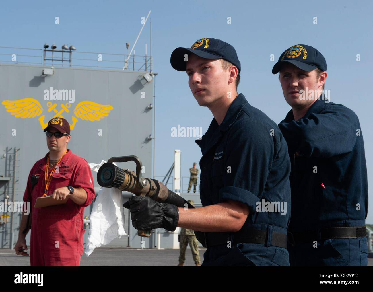 210712-N-LK667-0096 STAZIONE NAVALE ROTA, Spagna (12 luglio 2021) Damage Controlman 1a classe Gregory Wilson, a sinistra, valuta le prestazioni di Airman Ryan o'Sullivan, centro, E Aviation Boatswain's Mate (Fuel) Airman Bradley Lawson mentre partecipano a un trivello di salvataggio e crash sul ponte di volo della USS Hershel 'Woody' Williams (ESB 4) 12 giugno 2021. La Hershel 'Woody' Williams partirà da Rota, Spagna per un dispiegamento programmato nell'area della Sixth Fleet degli Stati Uniti di operazioni a sostegno degli interessi e della sicurezza nazionali degli Stati Uniti in Europa e Africa. Foto Stock