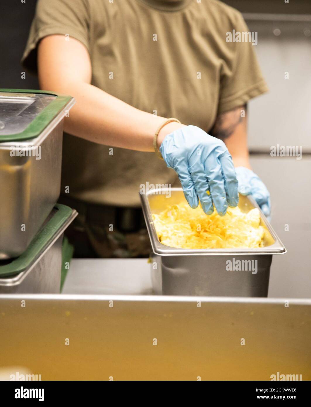 SGT. Paige Baschke, G-Co., 29th Brigade Support Battaglione, Arizona National Guard, mette una manciata di formaggio cheddar per finire una partita di uova strapazzate appena cotte prima di essere imballato per la distribuzione ad alcuni dei 584 guardiani Arizona sparsi in tutto Camp Navajo, Bellemont, Ariz., il 14 luglio. I 92Gs, Food Service Specialists, della G-Co., hanno recentemente concluso come secondi classificati nel Philip A. Connelly Award Competition, un Department of Defense Competition per vedere chi sono i migliori Food Service Specialist dell'esercito. Foto Stock
