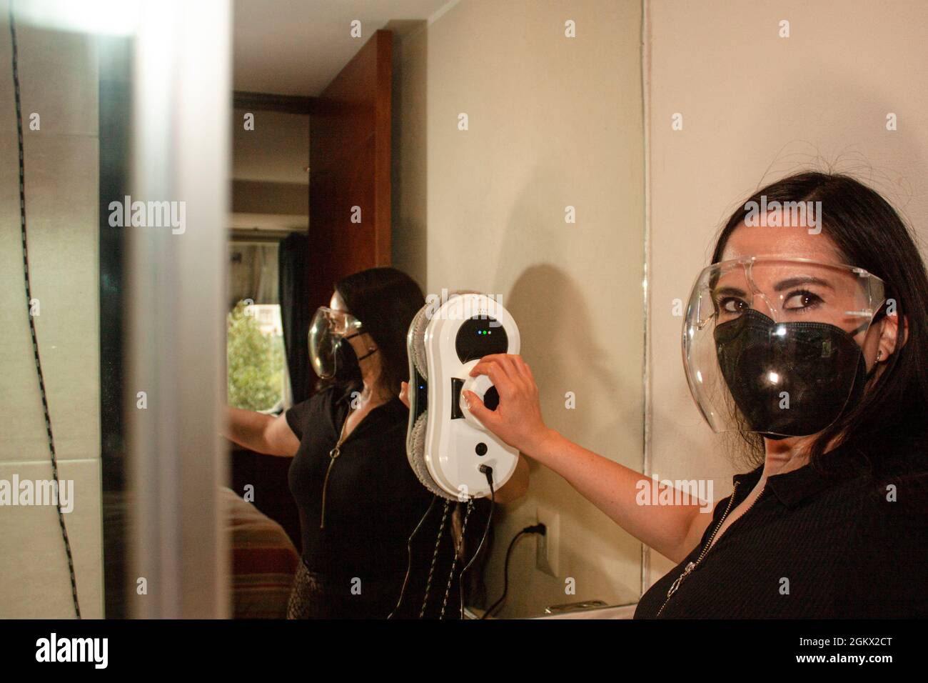 Donna che pulisce il lavoratore con le misure igieniche della nuova vita contro il coronavirus SARS COV 2 usando maschera copre bocche in Città del Messico utilizza lo zio robot Foto Stock