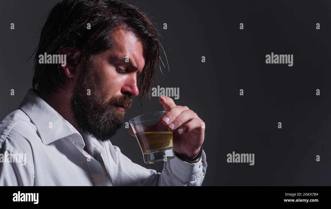 L'uomo al barbuto beve whiskey, brandy o cognac. Degustazione e degustazione. Alcol forte. Un sommelier assaggia un drink. Foto Stock