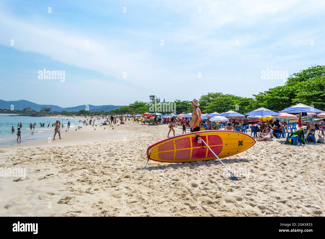 Una tavola da surf nella sabbia a Itaipu Beach, Rio de Janeiro, Brasile. I turisti sono visti fuori e circa questa zona. Il luogo famoso è un grande attra turistico Foto Stock